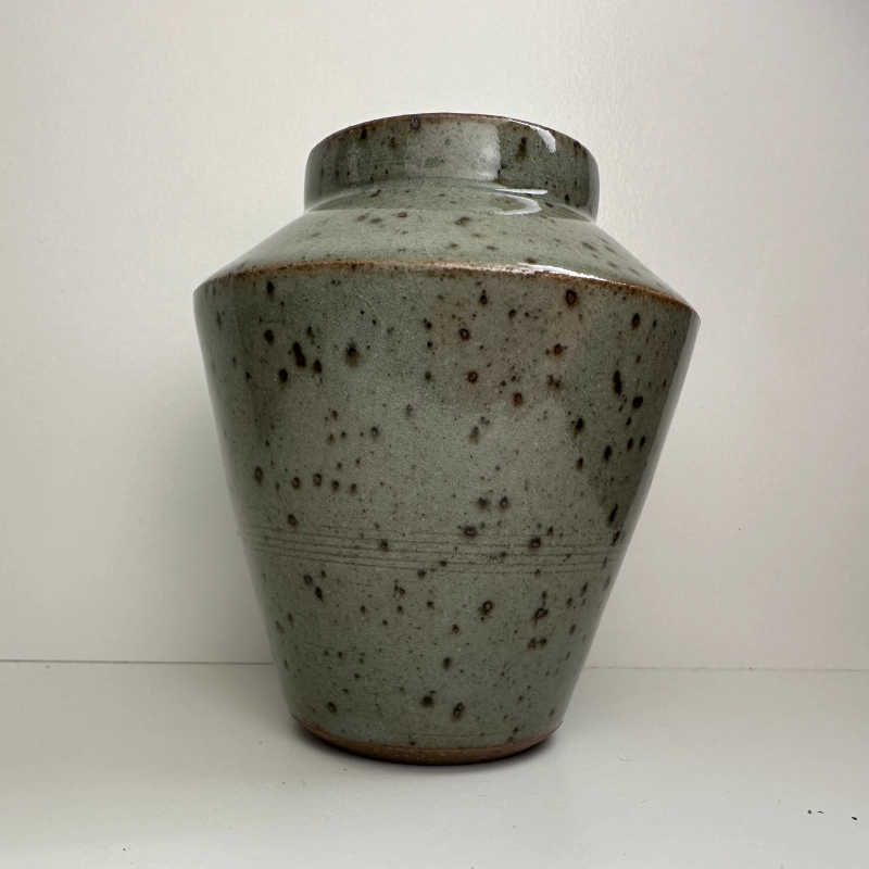 A small,  angular vase with a sage green glaze and brown iron-speckles.